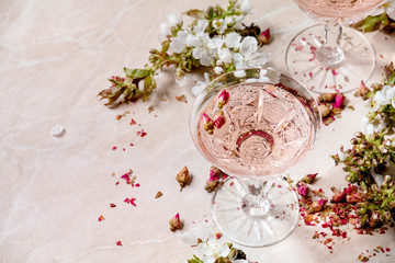 Crystal glasses of pink rose champagne, cider or lemonade with dry rose buds. Blossom cherry...
