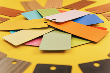 round composition of color design cards for selecting material and color on a yellow paper background, copy space