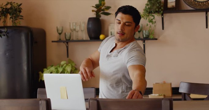 Hispanic male recieving work conference video call while cooking at home. Remote working from home, quarantine, coronavirus pandemic