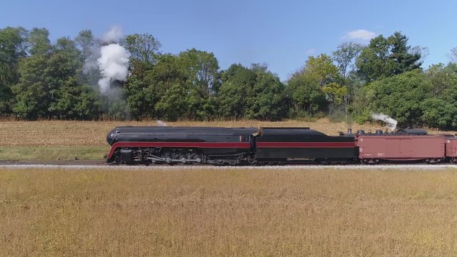 Aerial View of an Antique Restored Steam Engine Backing up Blowing Smoke with freight Cars on a siding on a Sunny Summer Day
