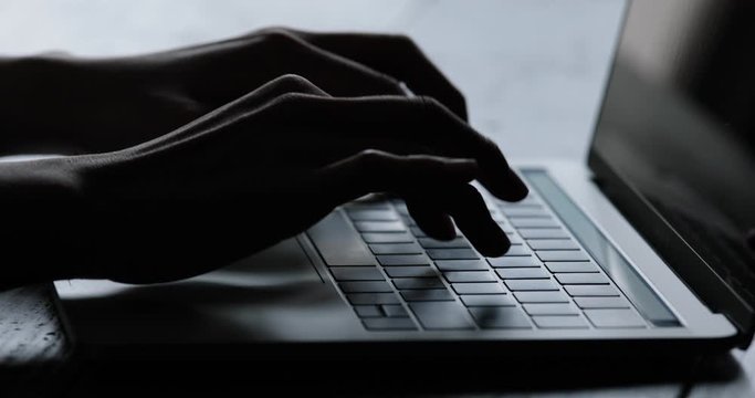 暗い部屋の中でパソコン作業をする若い女性のシルエット姿