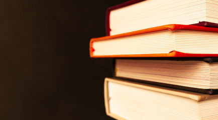 Stack of books with selective focus on black background with copy space in vintage style. Banner format. Home education, learning and studying