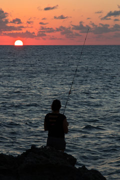 silhouette of a fisherman at sunset