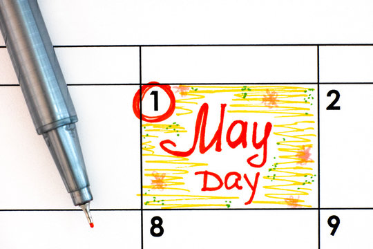 Reminder May Day in calendar with pen.