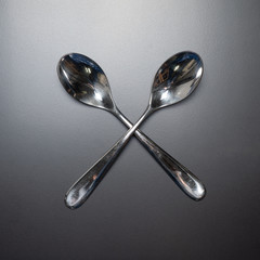 crossed spoons on a grey background 