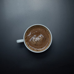 hot chocolate type drink in a white cup on a black background 