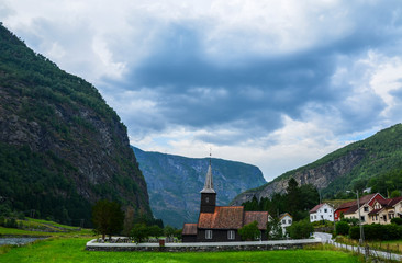Fototapeta na wymiar View of the Old wooden Flam Church or Flam Kyrkje and beautiful mountains on background on a cloudy summer day. Sognefjord, Norway