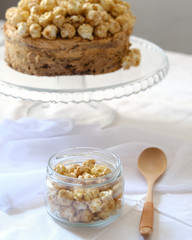 Cake with sweet caramel and caramel popcorn on the cake pan, on the table with a white tablecloth. Light photography