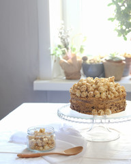 Cake with sweet caramel and caramel popcorn on the cake pan, on the table with a white tablecloth. Light photography