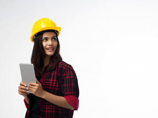 Young woman engineer standing at the left side of background,wearing yellow safety helmet ,holding tabletn hand,littler smile,portrait of model posing