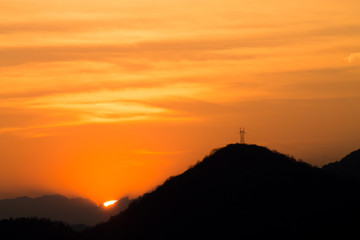 Outline of mountains at sunset with electric pylon