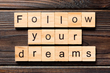 Follow your dreams word written on wood block. Follow your dreams text on wooden table for your desing, Top view concept