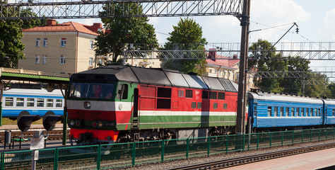 The image of locomotive with passenger vagons in station.