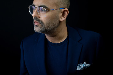 Bearded man in a t shirt and suit jacket with pocket square in retro glasses. 