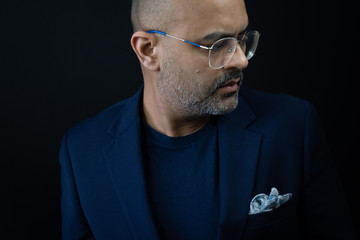 Bearded man in a t shirt and suit jacket with pocket square in retro glasses. 
