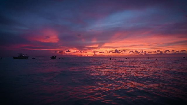 Fantastic sunset over the sea of many colors. People in the water and on boats photograph the sunset in Isla Mujeres Mexico