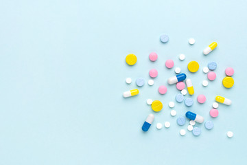 Colorful pharmaceutical medicine pills and tablets on blue background. Medicine flat lay.