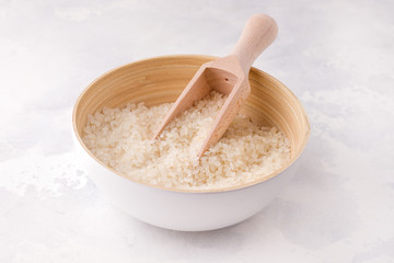 Rice in a bowl with a scoop on a white background.