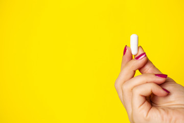 Woman holds white pill in her hand for weight loss