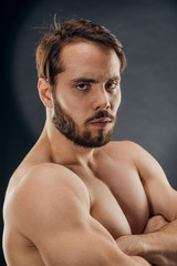 Fototapeta premium A handsome muscular man without a t-shirt poses for a photographer in a dark photo Studio. The concept of sport