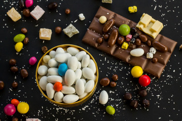 Traditional Turkish Hard Almond Candies designed on black surface with chocolate.Conceptual image of celebrations.