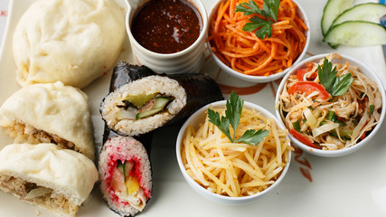 Korean nazionic dishes on a white plate. Pies, carrots and sauerkraut
