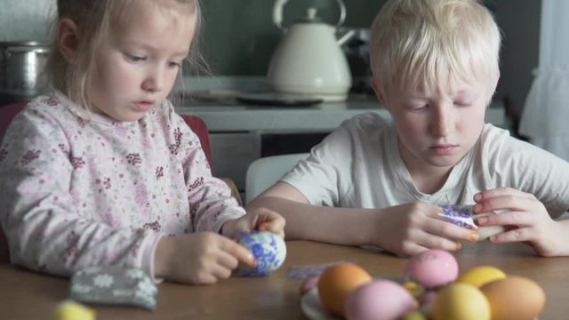 Children paint Easter eggs at home.