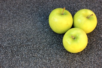 Yellow apples on a gray background. Row of green with one red apple among them on gray background. 4 Thinking out of the box concept. ripe green apples stone table background top view space for text