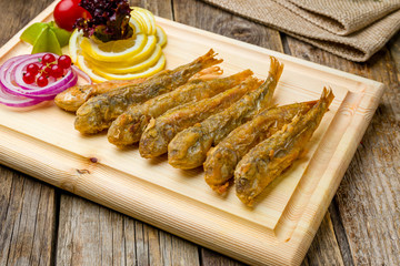 fried surmullet on board on wooden table