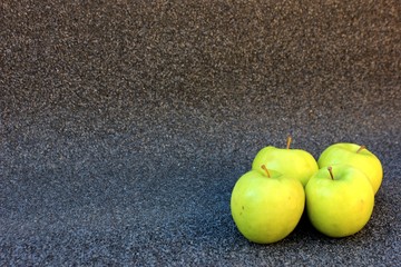 Yellow apples on a gray background. Row of green with one red apple among them on gray background. 4 Thinking out of the box concept. ripe green apples stone table background top view space for text