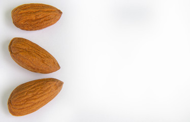 Nuts Almond kernels three pieces close-up lie on a white background on the left side.copyspace for text.