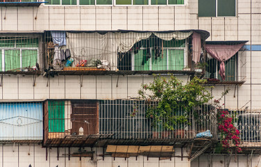 Baidicheng, China - May 7, 2010: Qutang Gorge on Yangtze River. Closeup of couple apartment balconies in multi-level highrise with metal grid fences in front. Stuff, laundry and flowers add color.