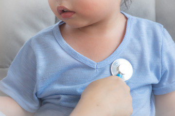 Little boy is examining by a doctor with stethoscope,Close-up of female pediatrician auscultating child's chest, Happy little boy having fun while is being examined by doctor by stethoscope,Sick child