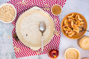 Empty dish pan after sweet breakfast. Food leftovers on table. Dirty unclean kitchenware. Overhead. Baked apples and oatmeal.
