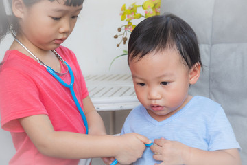 Little girl playing a doctor,boy and girl playing doctor and patient isolated,Two children play doctor and hospital using stethoscope,Sister and brother having fun at home or preschool,Tool doctor.