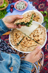 Qutab - Azerbaidzhan baked flatbread with greens and herbs. Vegan food. Woman hands hold a piece. 