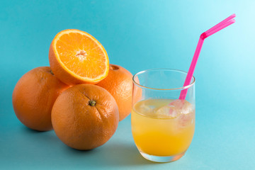 orange juice, oranges and half orange on blue background
