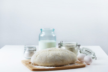 dough lies on the table, next to flour, eggs, milk. bakery products