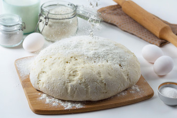 the dough lies on the table, next to a wooden rolling pin, flour and ingredients, pastries