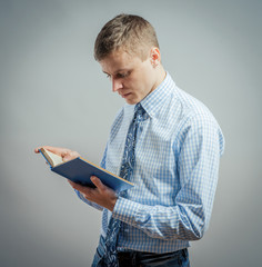 Portrait of young man reading isolated over gray background