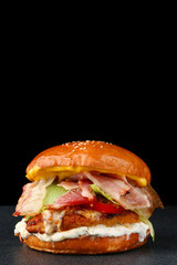 tasty burger with chicken on dark isolated background. Homemade hamburger or burger with fresh vegetables and cheese