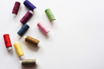 Fototapeta na wymiar Colored sewing threads on a white background, top view