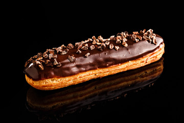 Classic chocolate eclair with chocolate spread and chocolate tidbits on top. Confectionery photography concept.