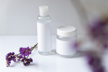 Cosmetic bottle for liquid, cream, gel, lotion. Hand sanitizer. Organic natural science beauty product. Battle with purple flower on white background