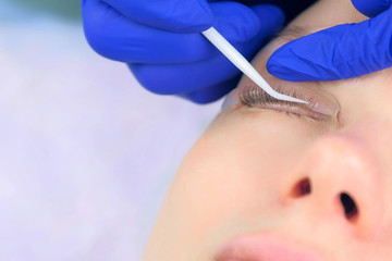 Cosmetologist bending lashes with needle into curlers, lift eyelashes laminaton procedure in beauty...