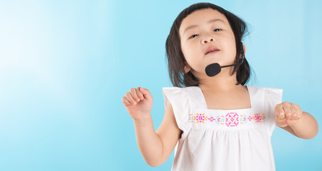 Cute Asian girl wearing voice headphones with a microphone and copy space.