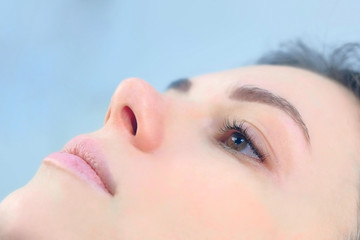 Face of young woman after lash laminating and painting eyebrows, side view. Closeup portrait of...
