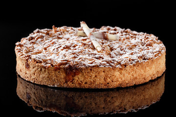 Apple cake with sugar powder on top and rolled white chocolate confectionery decor. Photography for bakery menu concept.
