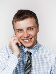 Closeup portrait of young businessman using mobile phone, smiling.