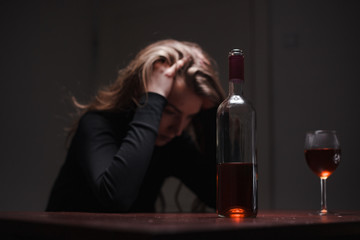 Young beautiful woman in severe depression, drinking alcohol. The concept of abuse and alcoholism. Alcoholic woman with bottle and glass of wine. 